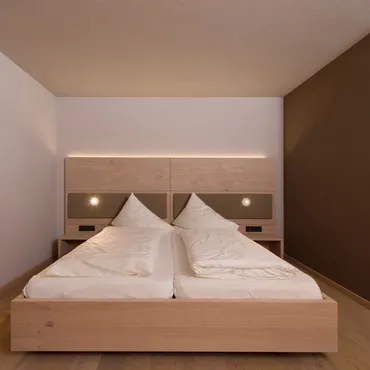 Hammerspitze Modern hotel room with double bed, wooden furniture, and minimal decor